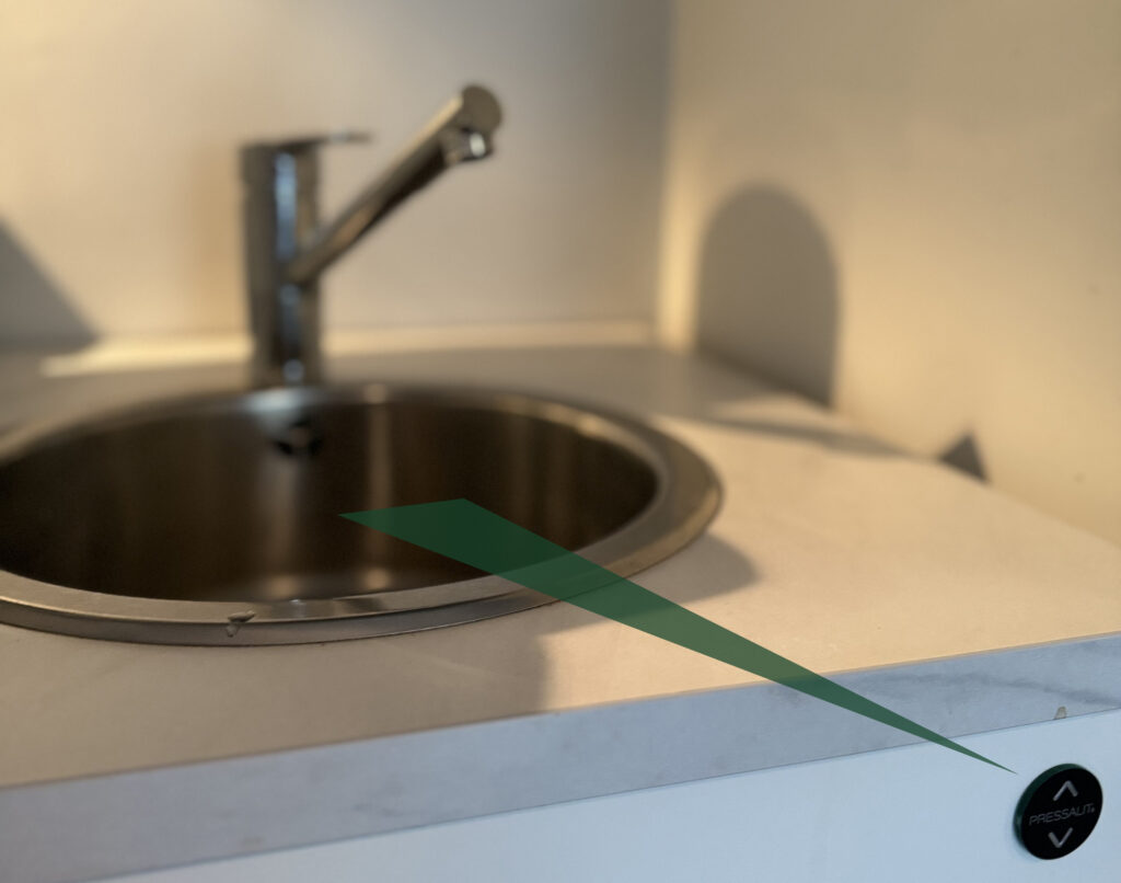 Mynd af eldhúsvaski og hnappi með örum, upp og niður.